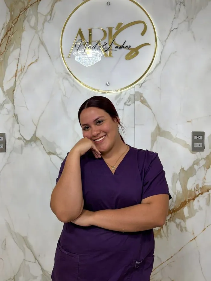 Ari, fundadora del salón, frente al logo de Ari’s Nails & Lashes